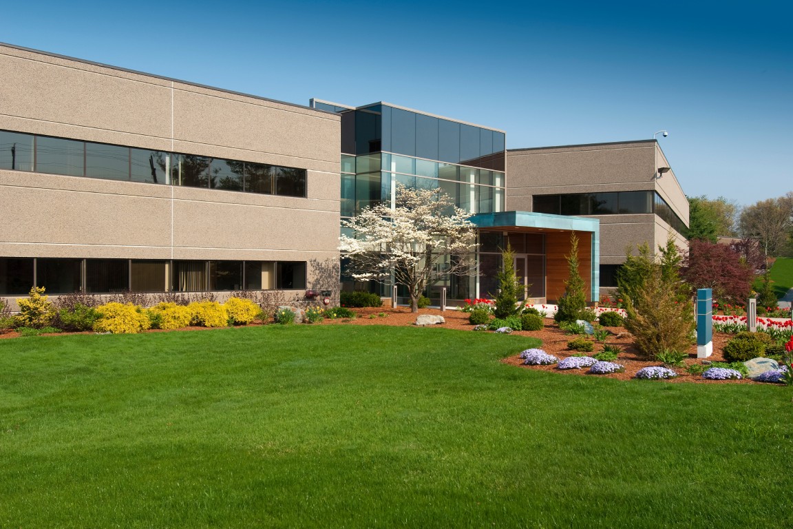 A modern commercial building in the summer with a well-maintained appearance and beautiful landscaping that looks inviting to customers.